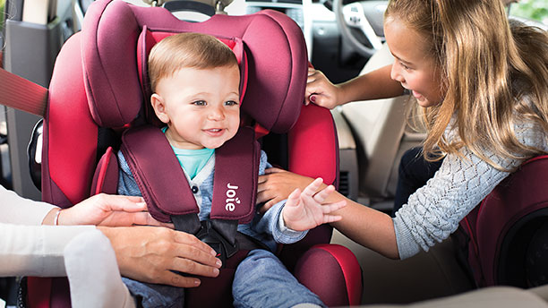 A little girl with a baby boy in a Joie car seat