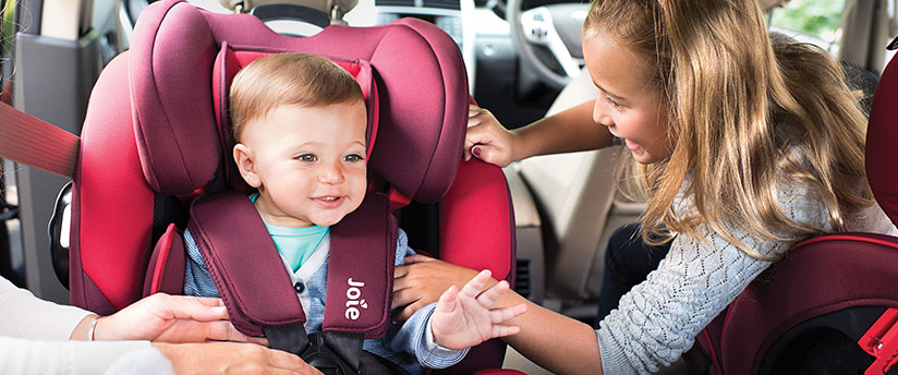A little girl with a baby boy in a Joie car seat